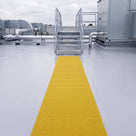 Single straight run of yellow embedded walkway matting bedded flush into a liquid-applied roof coating, leading to the foot of a plant access stair on a flat roof