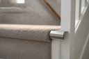 Inox brushed aluminium stair nosing end cap fitted to a carpeted staircase edge in a UK home hallway