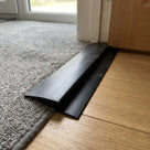 Close view of the black PVC ramp edging profile, showing the sloped ramp face and the flat lip that sits under the mat edge