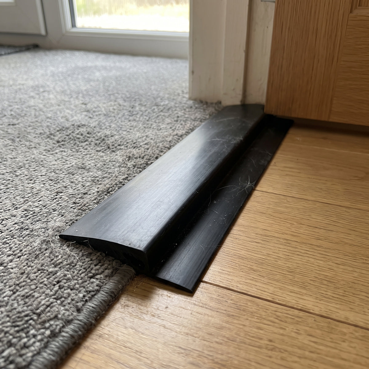 Close view of the black PVC ramp edging profile, showing the sloped ramp face and the flat lip that sits under the mat edge