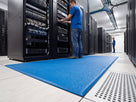 Blue static-dissipative anti-fatigue matting laid in a data centre cold aisle in front of a server rack