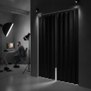 Black strip curtain across a photo studio opening, photographer at a monitor with lighting rigs