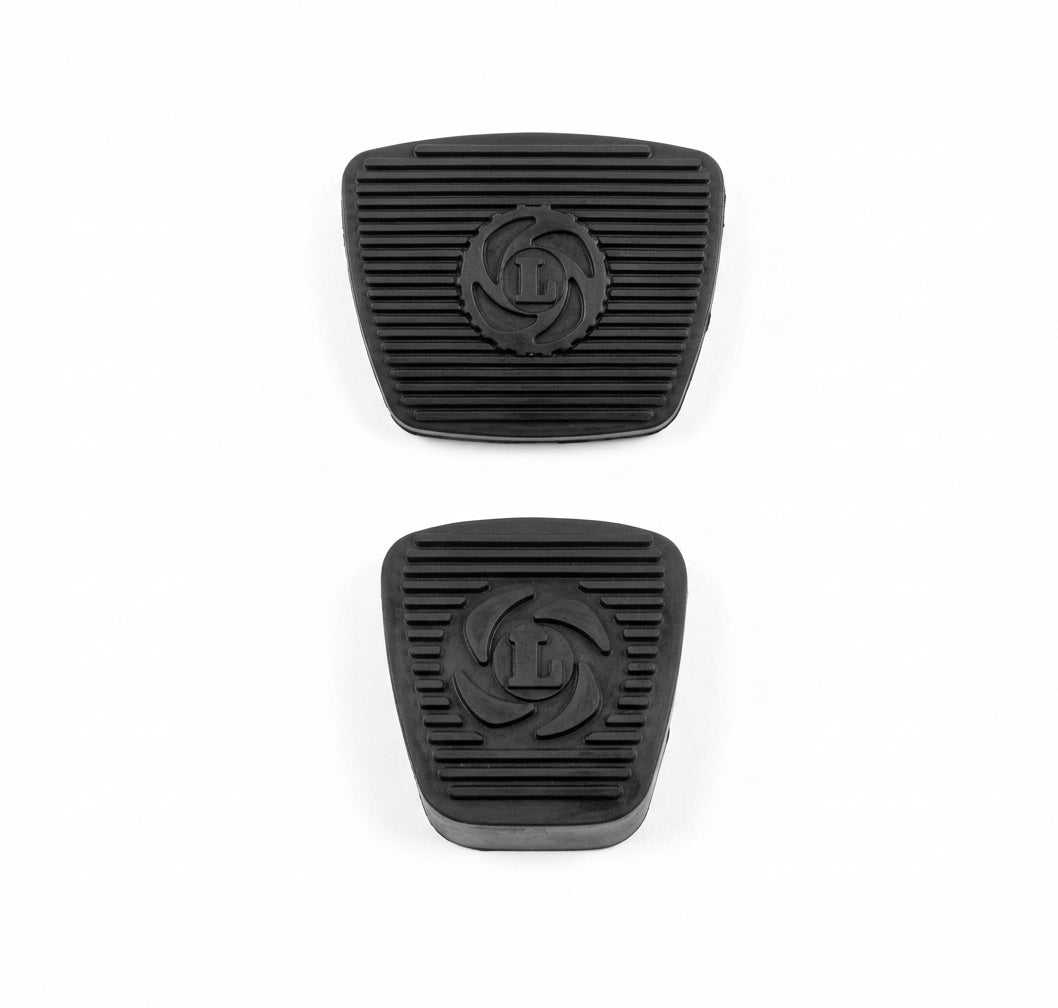 Pair of black ribbed rubber pedal pads with embossed logo, studio shot