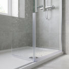 Clear fin seal down the vertical edge of a wet glass shower panel, grey tiles and a white tray behind