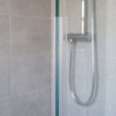 Clear vertical seal on the upright edge of 4-6mm glass, soft fin closing the gap to the wall