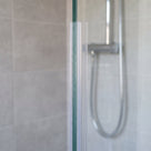 Clear vertical seal on the upright edge of 4-6mm glass, soft fin closing the gap to the wall