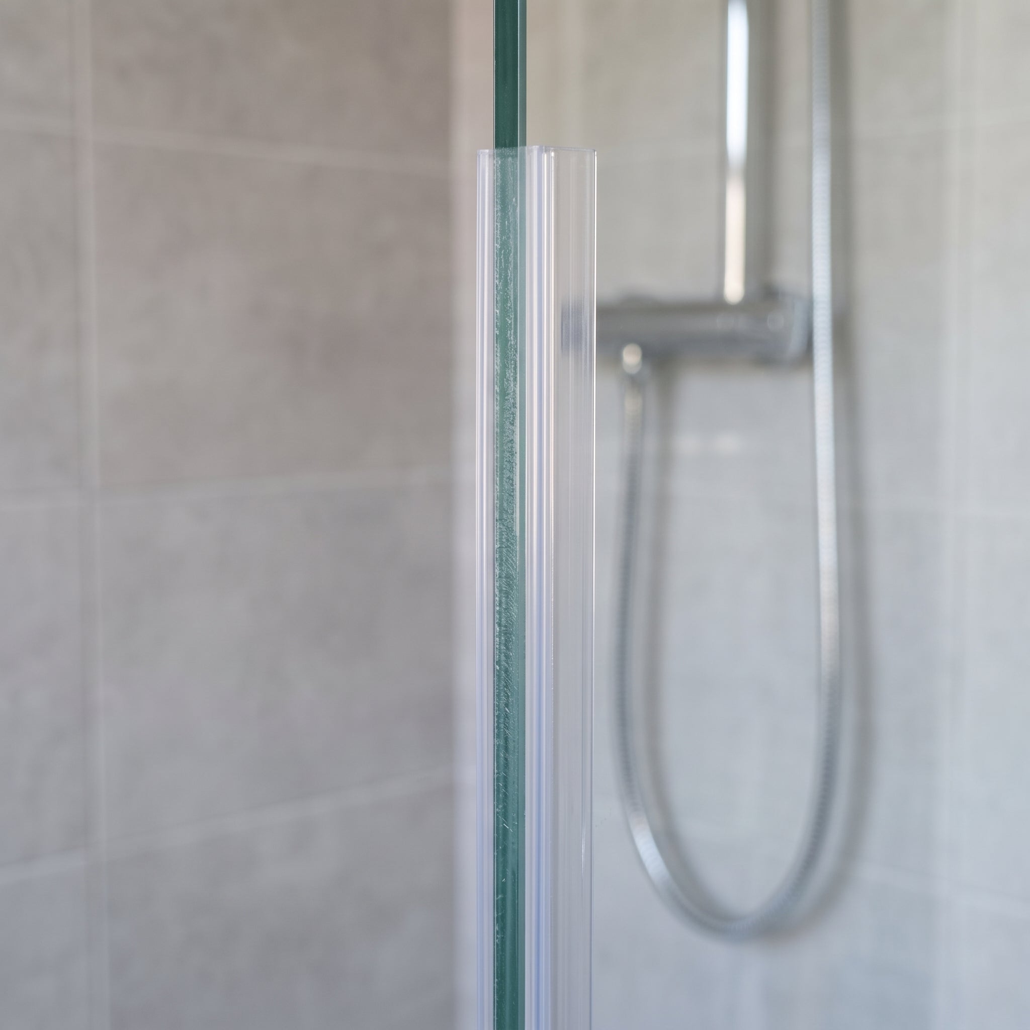 Clear vertical seal on the upright edge of 4-6mm glass, soft fin closing the gap to the wall