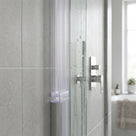 Clear fin seal down a glass shower panel upright against grey tiles, chrome valve and window behind
