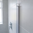 Clear seal fitted down the upright edge of a glass shower screen against a grey tiled wall