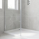 Grey stone-tiled shower recess, chrome-edged glass screen on a white tray, thermostatic valve and window