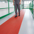 Red fine-rib PVC runner marking the walkway along a clean factory mezzanine with green handrails