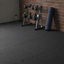 Black diamond-plate interlocking EVA foam floor tiles fitted in a home gym corner with a dumbbell rack and rolled yoga mat