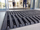 Dark grey open-grid entrance matting in an office reception matwell