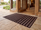 Dark brown open-grid entrance matting at a timber-framed hotel doorway