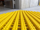 Bright yellow open-grid entrance matting at an industrial personnel doorway