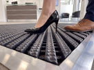Close-up of a stiletto heel and a leather brogue on Frontrunner Entry matting, showing it is wheel and heel proof