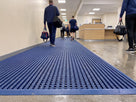 Oxford blue Frontrunner Entry matting with a ramped edge running the length of a leisure centre entrance, grit visible in the open channels below the tread