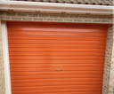 Orange gloss paint freshly applied to an up-and-over garage door on a UK house