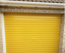 Yellow gloss paint freshly applied to an up-and-over garage door on a UK house