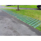 Green grass protection mesh pinned along a grass verge beside a tarmac drive to stop vehicles rutting it