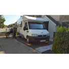 White motorhome parked on a residential driveway laid with green grass protection mesh over the ground