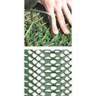 Hand pressing a steel U-pin through green grass protection mesh, with a close-up of the mesh cells below