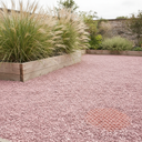 Pink gravel patio area beside a raised timber planter with the honeycomb stabilisation grid visible beneath the stone