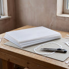 Stack of thin natural white HDPE sheets on a workbench with a gasket cut from one and a craft knife on a cutting mat