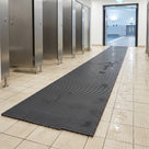 Dark grey Heronrib matting laid as a walkway across the wet tiled floor of a swimming pool changing village, running from the cubicle doors out towards the pool hall entrance.
