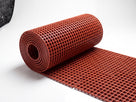 Roll of red open grid PVC matting partially unrolled on a white background showing the 15mm lattice