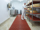 Red open grid matting in a dairy and cheese production room with whey and water running through the grid