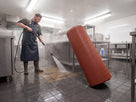 Matting rolled back on end while the kitchen floor beneath is pressure washed, showing it lifts by hand