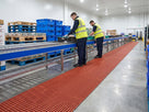 Long run of red open grid matting along a chilled food packing conveyor in a distribution warehouse