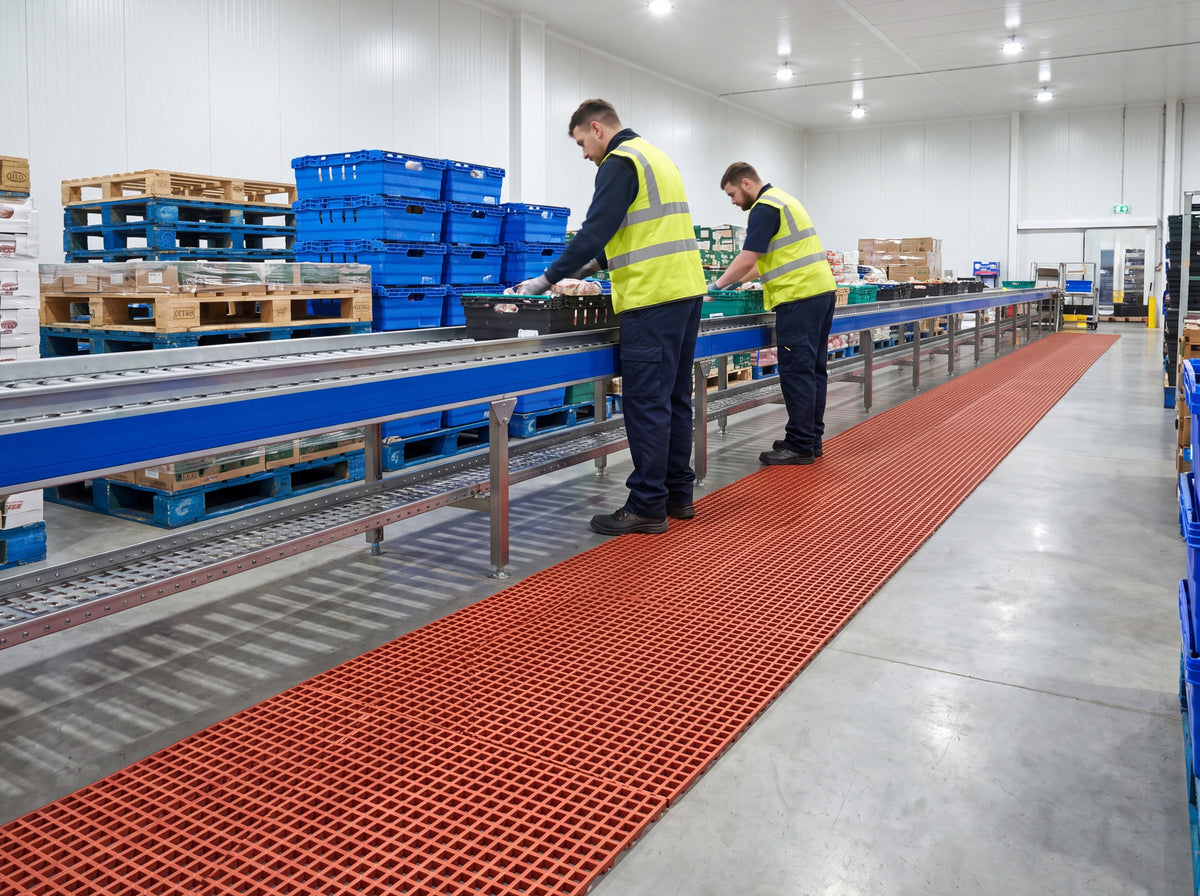Long run of red open grid matting along a chilled food packing conveyor in a distribution warehouse