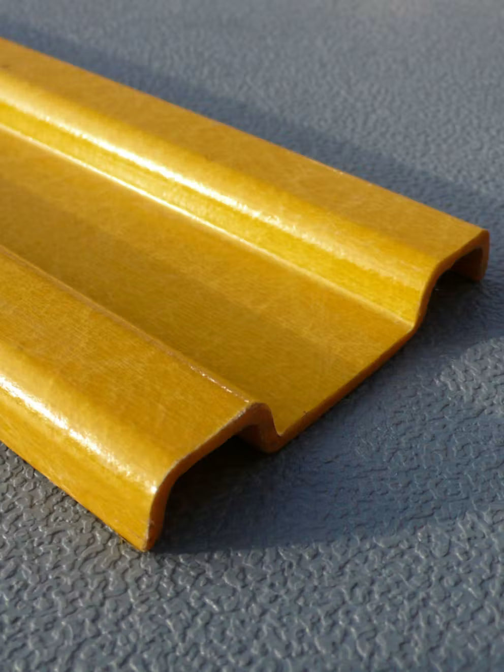 Two yellow pultruded GRP kick plates in W-section profile, angled close-up on a grey chequer plate floor