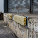 Yellow polyurethane loading dock buffers bolted along the concrete edge of a warehouse loading dock
