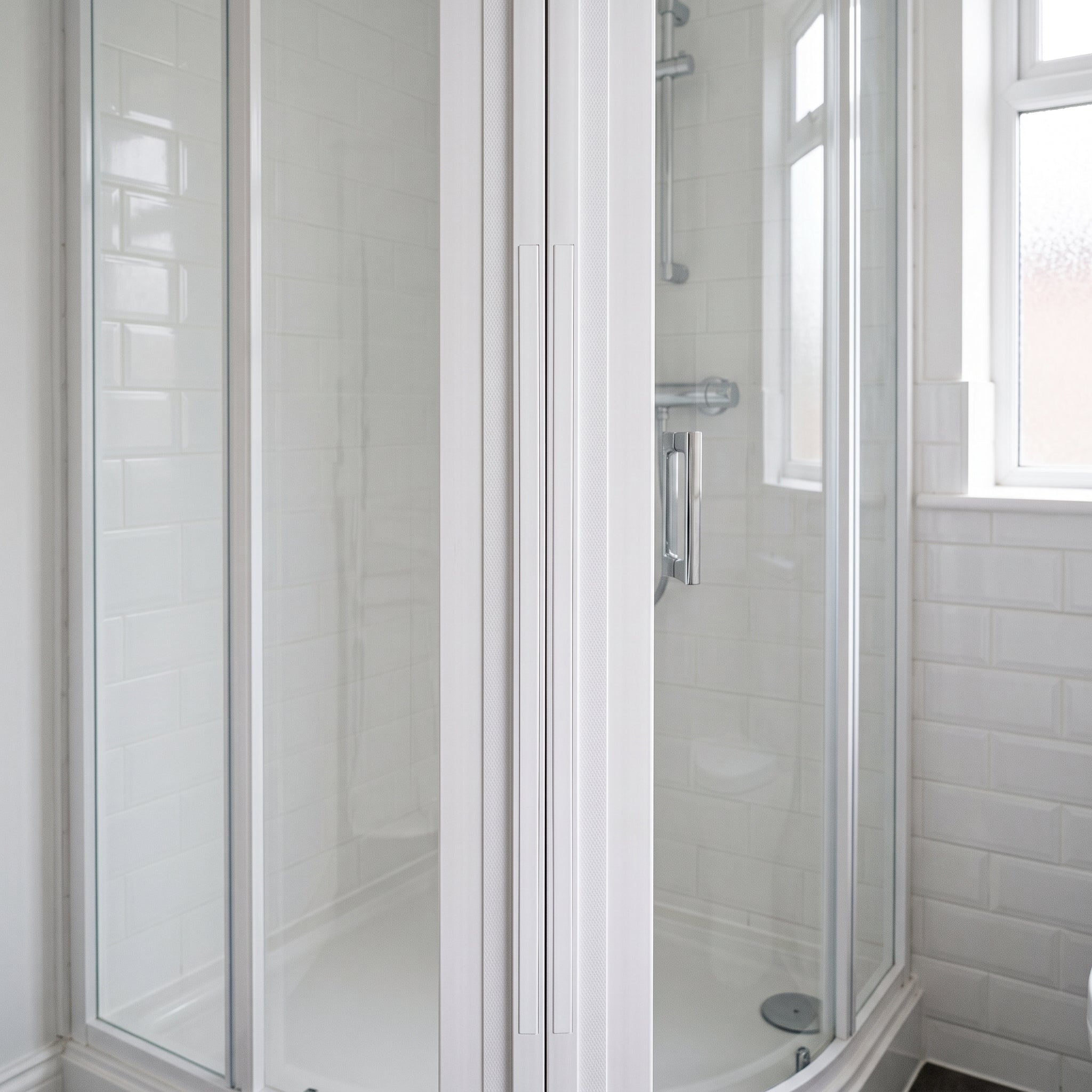 Pair of white MAG005 magnetic channel seals holding a quadrant shower door closed in one continuous vertical line