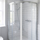 Chrome-framed quadrant shower enclosure with curved doors closed, chrome handles and white metro tiles