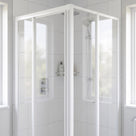 White-framed corner shower enclosure with the two door panels closed on the upright, white tiles and windows