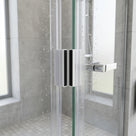 Clear seals with black magnet strips meeting on wet glass shower doors, chrome handle and grey tiles behind
