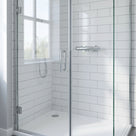 White metro-tiled corner shower enclosure with the glass door closed, seal not visible at this distance