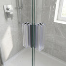 Two clear seals with dark magnet strips meeting at a wet glass corner join, grey marble tiles behind