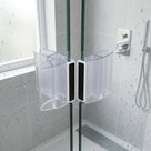 Two clear curved seals with black magnet strips meeting on wet glass shower doors, grey tiles behind