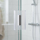 Two clear magnetic seal strips meeting on the closing edge of a wet glass shower door, black magnets showing
