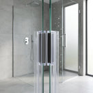Two clear magnetic seals with black magnet strips meeting where wet glass shower doors close, grey tiles behind