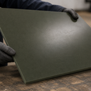 Olive-green Oilon sheet held by gloved hands, matt surface in a workshop