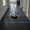 Black fluted boards taped over a hallway floor mid-decorating, stepladder, paint tray and roller on top