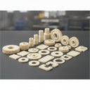 Cream nylon gears, bushes, spacers and machined plates arranged on a grey bench top