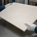 Cream-burgundy PE500 sheet held by gloved hands in a workshop