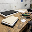 Black, white and beige polypropylene copolymer sheets stacked on a fabrication bench with a hot-air welder and a welded corner sample